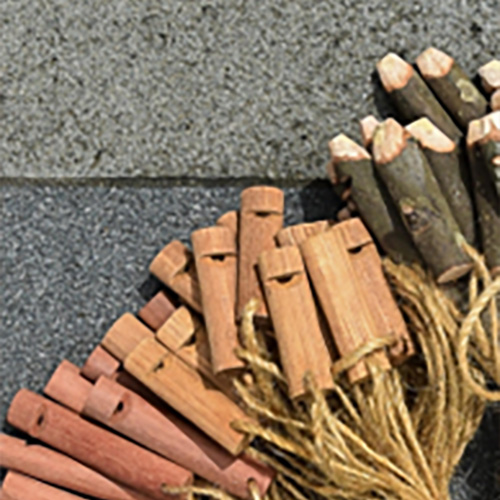 A pile of small wooden pocket whistles with cords, on stone