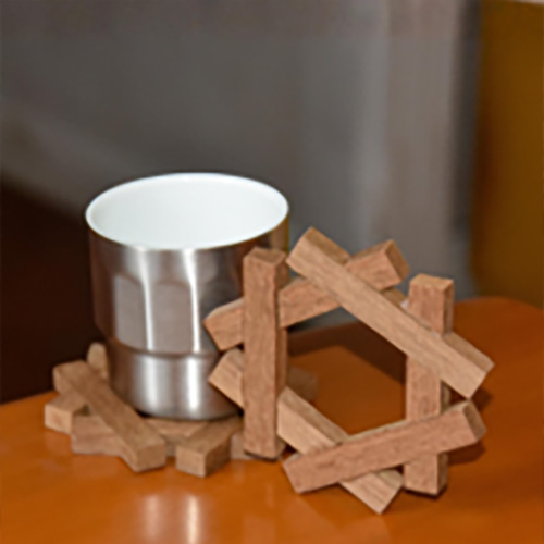 An interlocking geometric wooden coaster under a metal cup