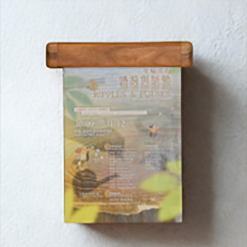 A wall-mounted wooden rail holding a printed exhibition card