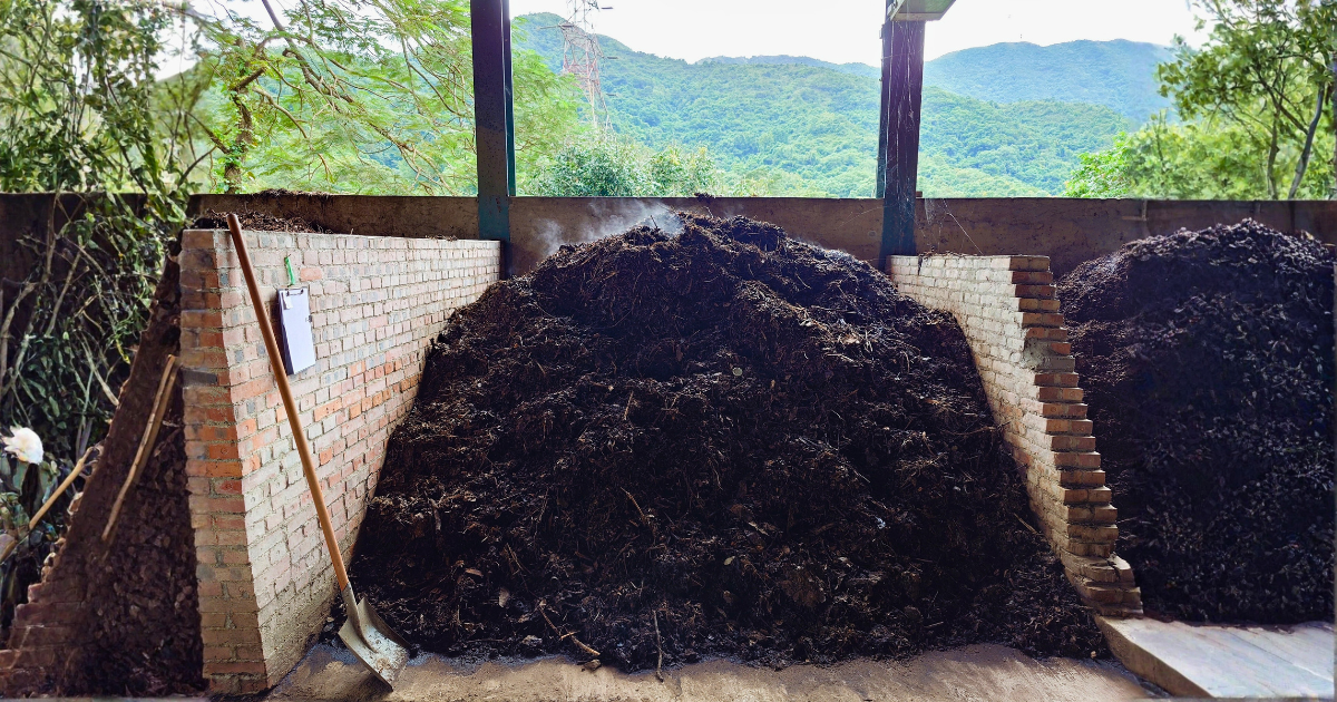 堆肥棚下的堆肥堆，遠處是山巒
