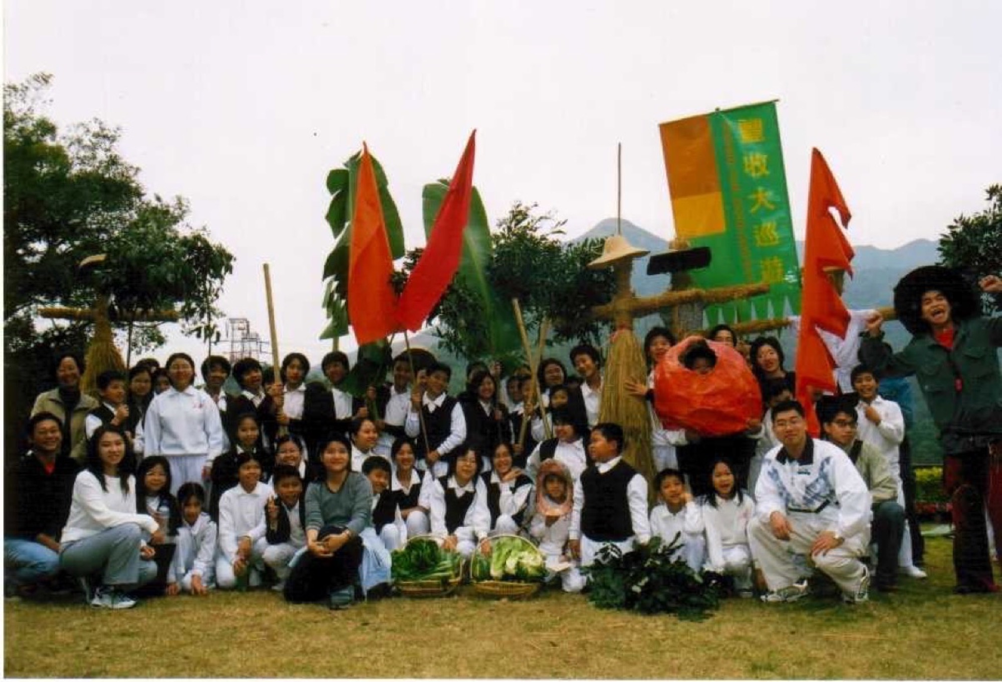 有機節參加者手持彩旗與稻草紮作，在「豐收大巡遊」橫額前合照